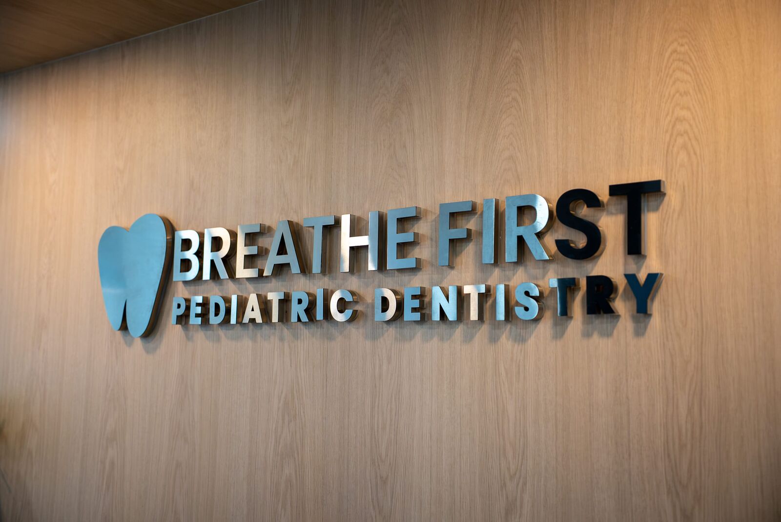 Breathe First Pediatric Dentistry sign on the wood-paneled wall